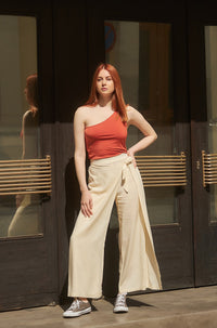Woman wearing the Magnolia Pants sewing pattern from The Patterns Room on The Fold Line. A trouser pattern made in soft linen, viscose, light denim or crepe fabrics, featuring a wide leg with an extra front skirt layer tied at the left side, encased elast
