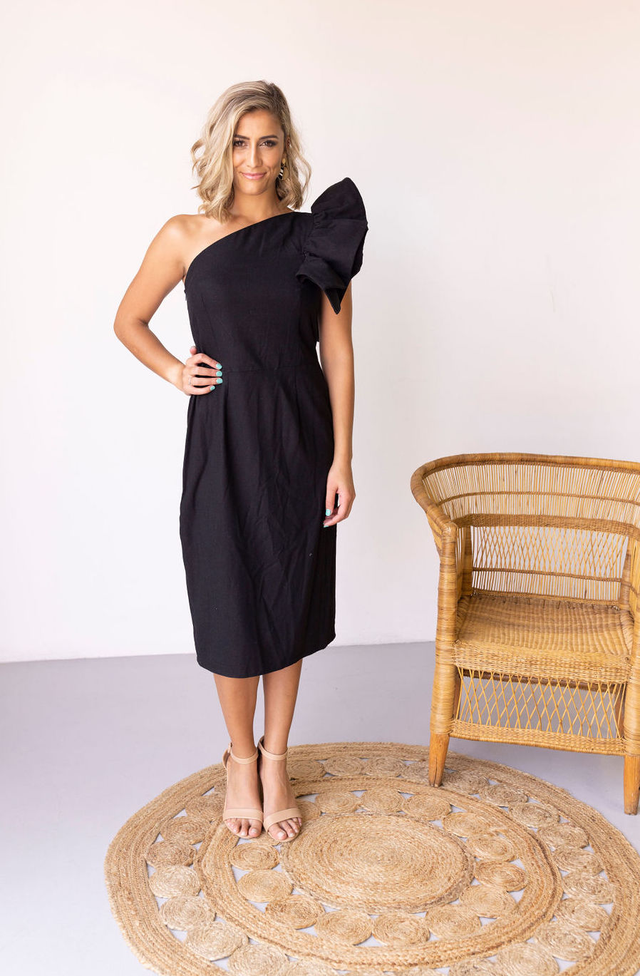 Woman wearing the Mari Dress sewing pattern from Pattern Sewciety on The Fold Line. A dress pattern made in cotton, linen or rayon fabrics, featuring a sheath style silhouette, front and back waist darts, asymmetric neckline with shoulder ruffle and below
