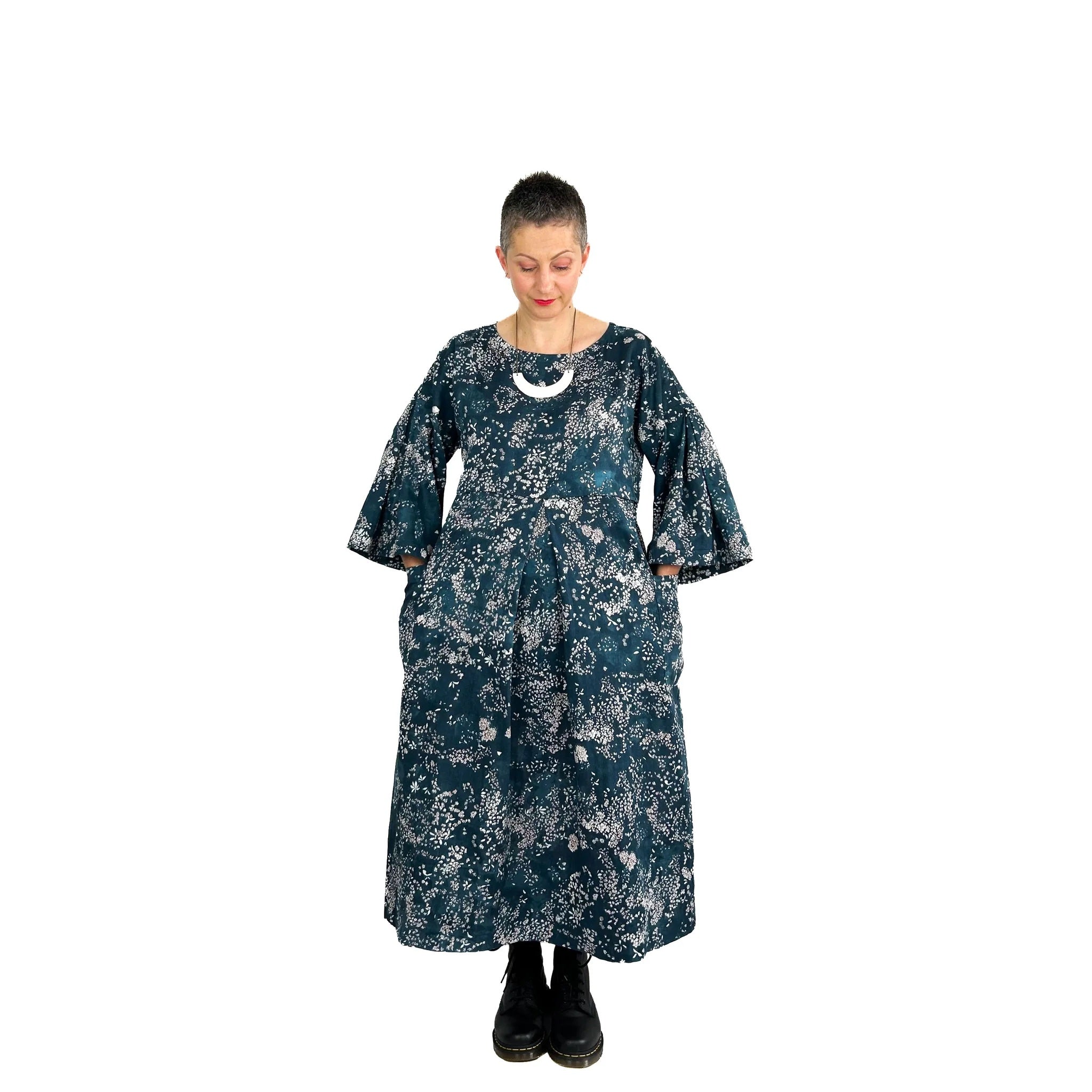Woman wearing the Martha Dress sewing pattern from Dhurata Davies Patterns on The Fold Line. A dress pattern made in linen or woven fabrics, featuring a relaxed fit, ¾ length wide sleeves, round neckline, patch pockets, deep inverted pleat at the shoulder