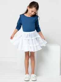 Child wearing the Children’s Melody Skirt sewing pattern from Style Arc on The Fold Line. A Skirt pattern made in rayon, or cotton fabrics, featuring three-tiers, gathered skirt with drawstring, elasticated waist, narrow frills and above knee length.