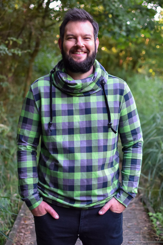 Man wearing the Men's Cottesloe Cowl Top sewing pattern from Waves & Wild on The Fold Line. A top pattern made in french terry or sweatshirt fleece fabrics, featuring a relaxed fit, cowl neck with drawstring and full length sleeves.