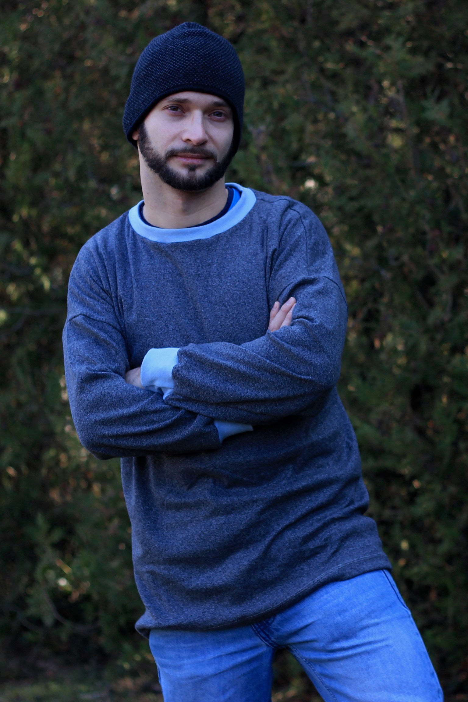 Man wearing the Men's Driftwood Dolman Sweatshirt sewing pattern from Waves and Wild on The Fold Line. A sweatshirt pattern made in medium-weight knit fabric, featuring a relaxed fit, long sleeves, round neck and ribbing to the neck and cuff.