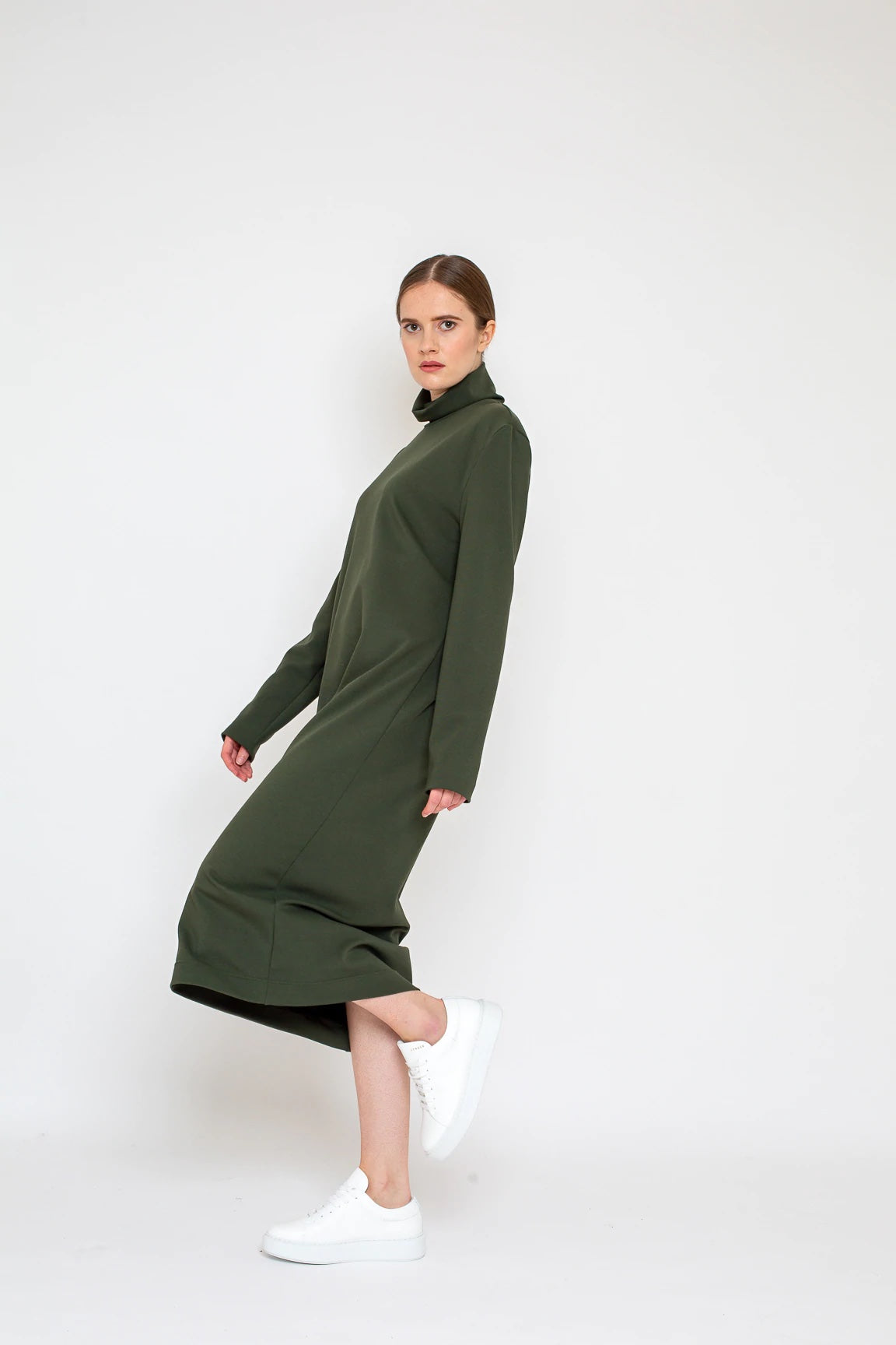 Woman wearing the Mila Dress sewing pattern from Bara Studio on The Fold Line. A dress pattern made in jersey, interlock or punta di roma fabrics, featuring a loose fit, turtleneck, longer than normal sleeves and midi length.