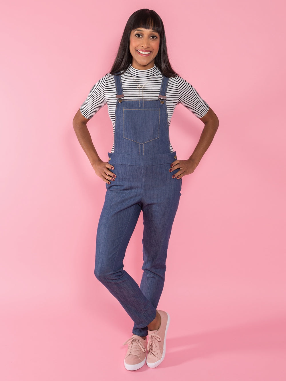 Woman wearing the Mila Dungarees sewing pattern from Tilly and the Buttons on The Fold Line. A dungarees pattern made in stretch denim, needlecord or cotton fabric, featuring a slim fit, side button openings, and patch pockets.