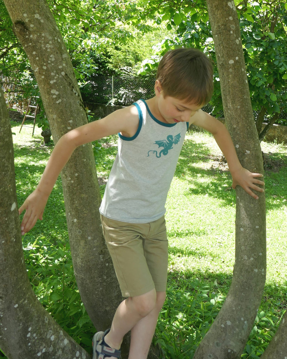 Child wearing the Child/Teen Milos Tank Top sewing pattern from Petits D'om on The Fold Line. A tank pattern made in jersey fabrics, featuring a rounded neckline, no sleeves and racer back.