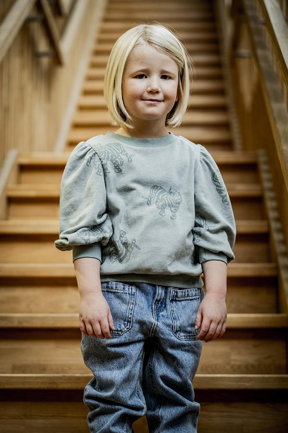 Child wearing the Child/Teen Minnie Top sewing pattern from Fibre Mood on The Fold Line. A jumper pattern made in French terry, sweatshirting or velvet jersey fabrics, featuring a round neckline, 3/4 length puffed sleeves, relaxed fit, ribbed neckline, he