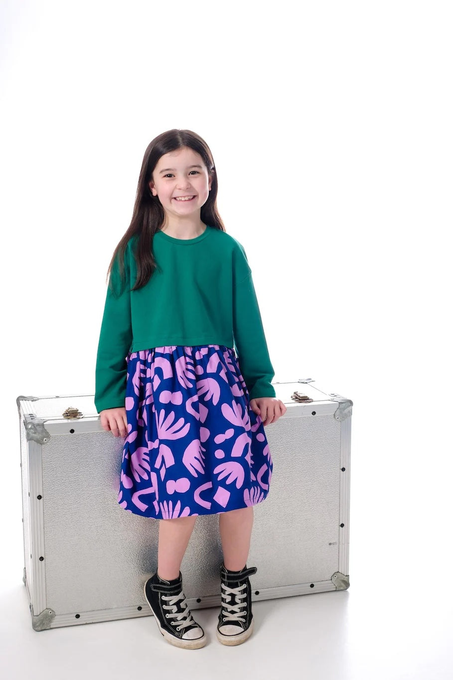 Girl wearing the Child/Teen Mizzle Dress sewing pattern from Little Rosy Cheeks on The Fold Line. A dress pattern made in knit fabric for the top and woven fabric for the skirt, featuring an oversized fit, round neck, long sleeves, gathered skirt, and poc