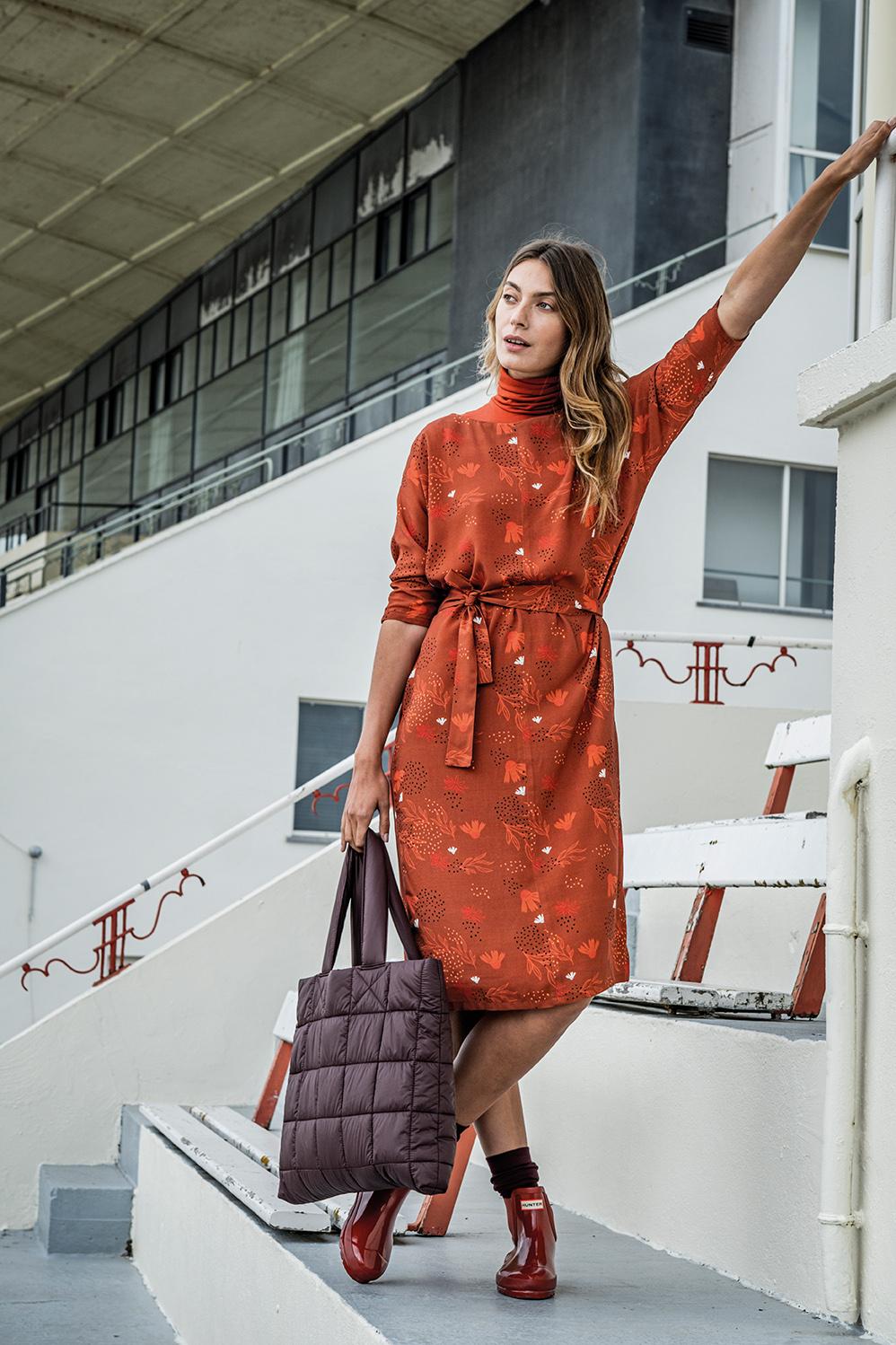 Woman wearing the Nanou Dress sewing pattern from Fibre Mood on The Fold Line. A dress pattern made in lyocell, jacquard, crepe, wools, suede, ribbed jersey, faux suede or velvet fabrics, featuring a straight cut, boat neckline, grown on bracelet length s