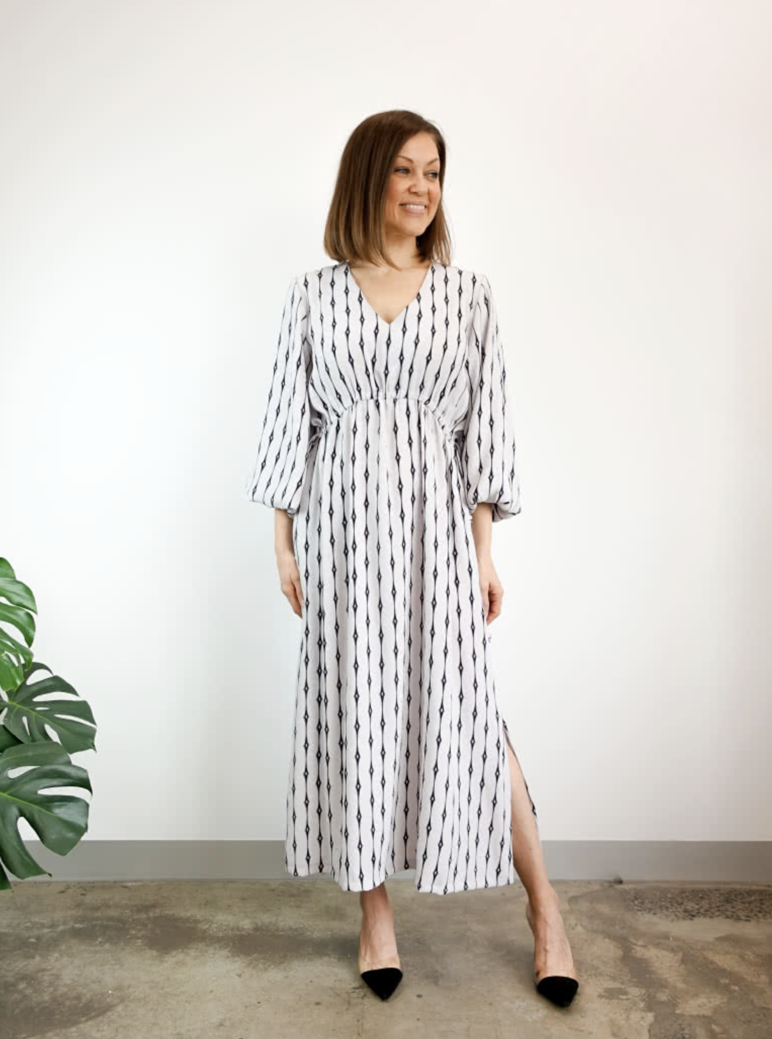 Woman wearing the Naomi Woven Dress sewing pattern from Style Arc on The Fold Line. A dress pattern made in silk, crepe or rayon fabrics, featuring a slip-on longline style, V-neck, angled waist seam with drawstring, 7/8-length sleeves with elastic cuffs,