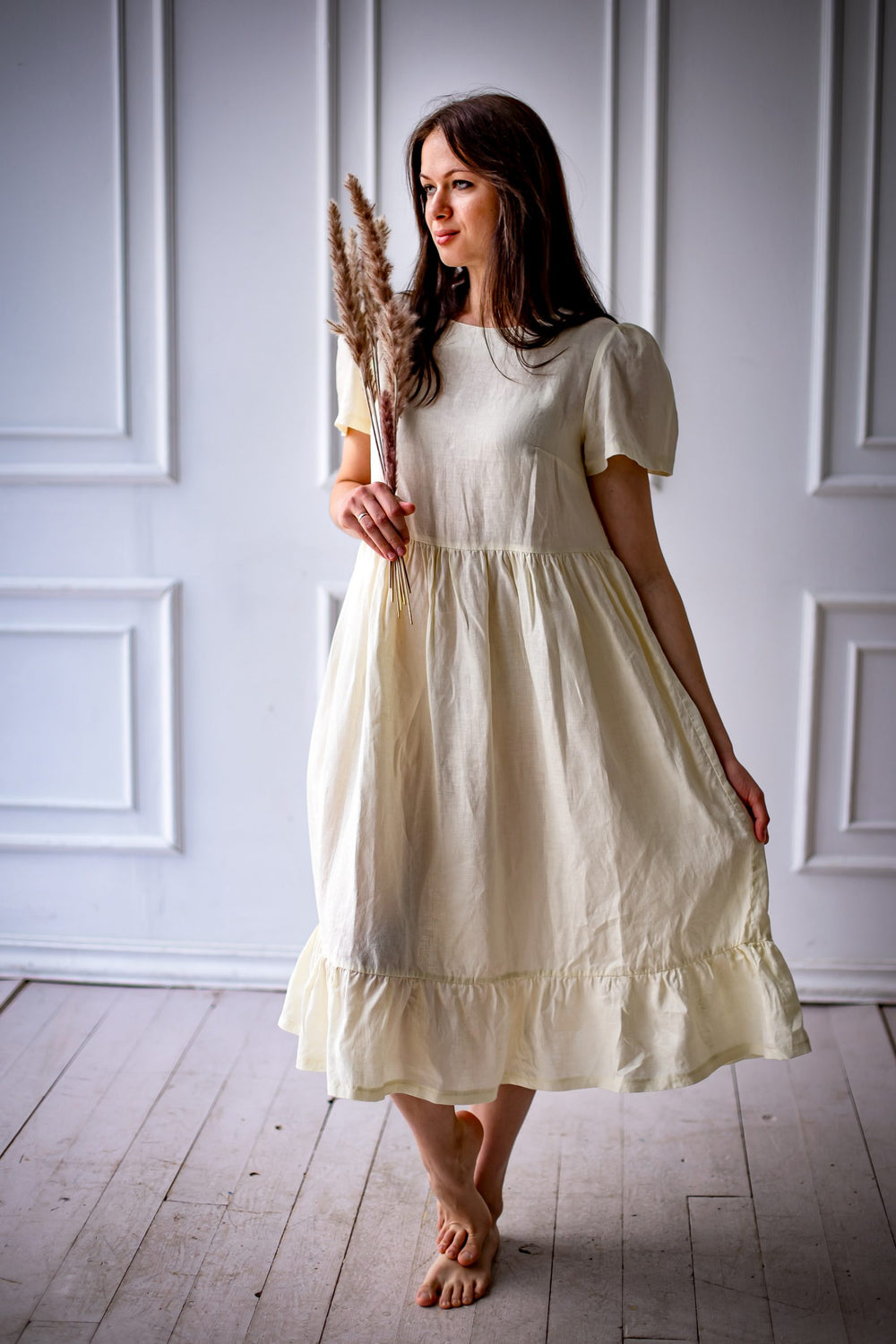 Woman wearing the Naya Dress sewing pattern from Kates Sewing Patterns on The Fold Line. A dress pattern made in cotton or linen fabrics, featuring a high waistline, bust darts, voluminous sleeves with gathers at the top, full skirt gathered at the waist 