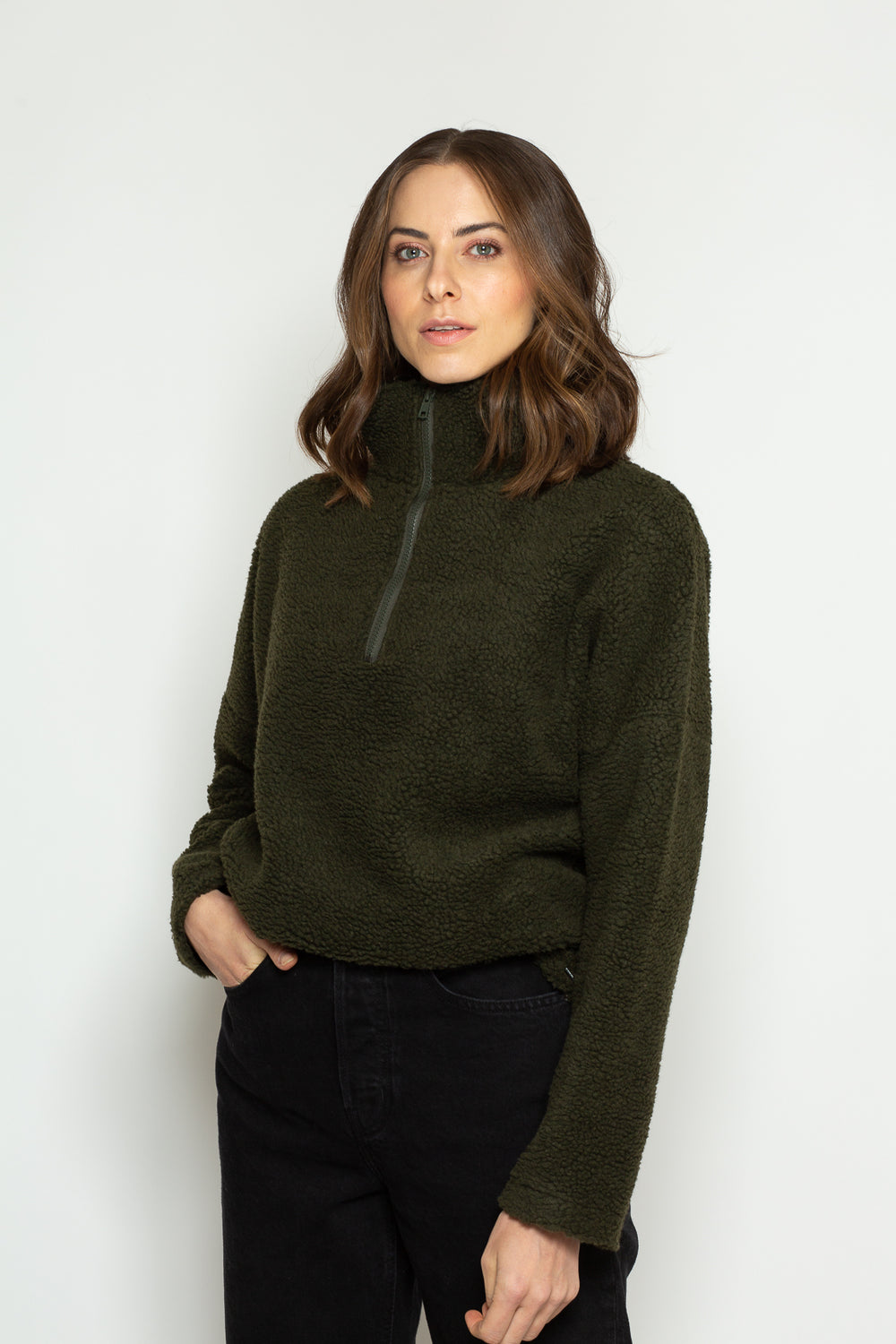 Woman wearing the Nela Zip-neck Sweater sewing pattern from Bara Studio on The Fold Line. A sweater pattern made in fleece, plush, teddy or heavy knit fabrics, featuring a full length sleeve, high neck, front zip opening, adjustable elasticated hem with t
