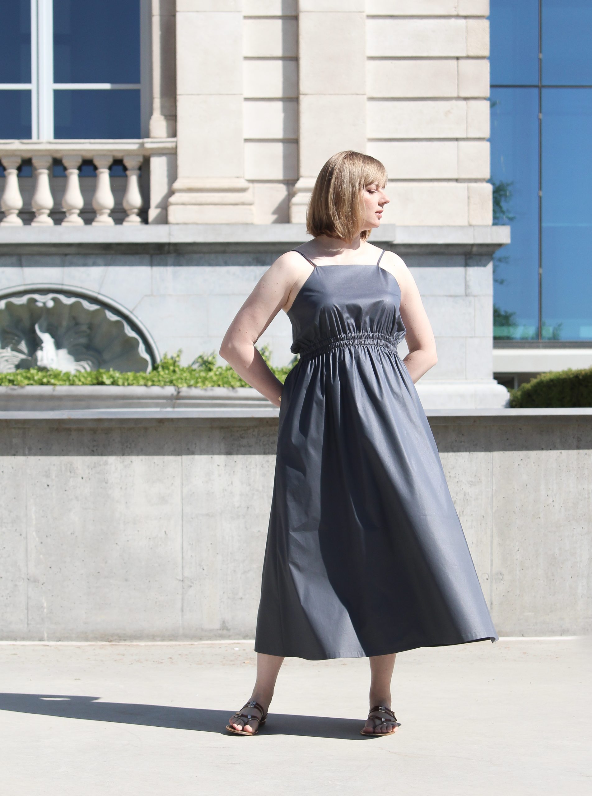 Woman wearing the Nina Dress sewing pattern from Lenaline Patterns on The Fold Line. A dress pattern made in cotton, cotton poplin, silk, linen or viscose fabrics, featuring an elasticated waist, in-seam pockets, adjustable spaghetti straps, midi length a