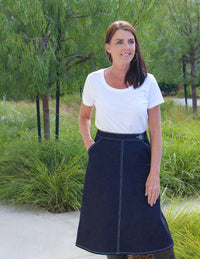 Woman wearing the No-Zip Skirt sewing pattern by Blue Dot Patterns. An A-line skirt pattern made in denim, twill, corduroy, suitings, sateen, poplin or linen fabrics, featuring a fitted waist, slash pockets, button and hook and eye closure.