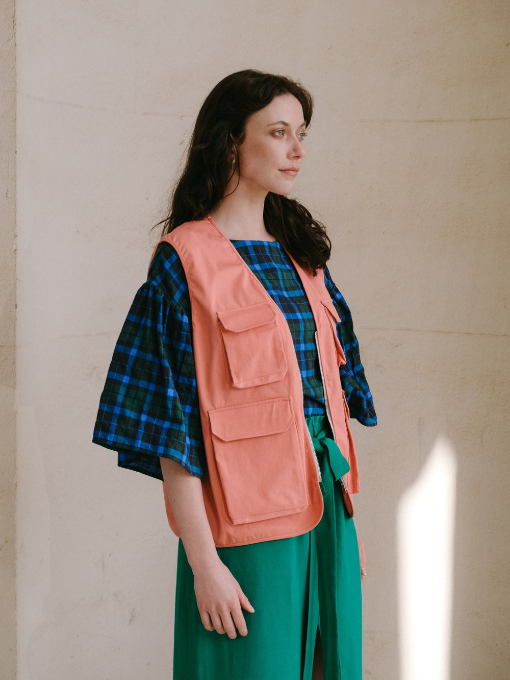 Woman wearing the Benly Utility Vest sewing pattern from Notches on The Fold Line. A vest pattern made in canvas, twill, denim, corduroy, nylon, quilted, or teddy fabric, featuring a hip length, oversized fit and pockets with flaps.