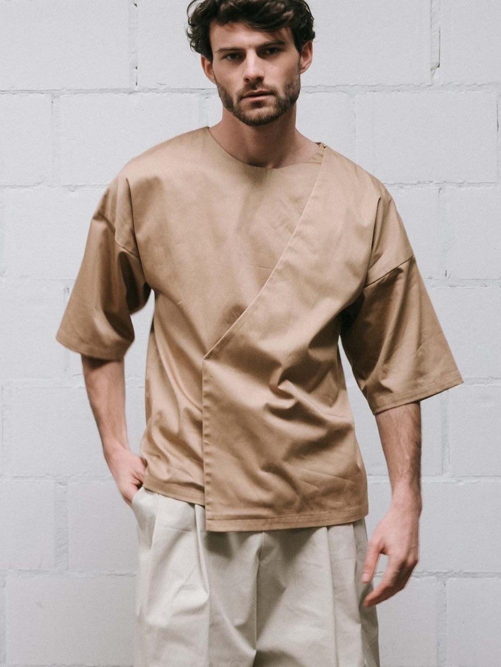 Man wearing the Men's Jack Shirt sewing pattern from Notches on The Fold Line. A shirt pattern made in cotton or linen fabric, featuring a round neckline, elbow length sleeves, and an overlapping front panel.