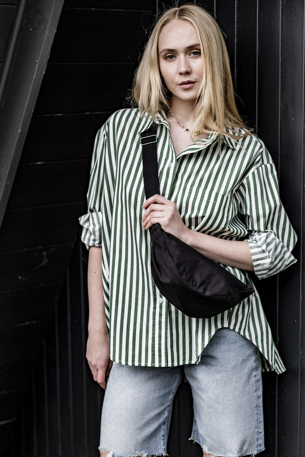 Woman wearing the Nousha Bag sewing pattern from Fibre Mood on The Fold Line. A bag pattern made in denim, corduroy, or heavyweight cotton fabrics, featuring an adjustable cross body strap, and zip closure.