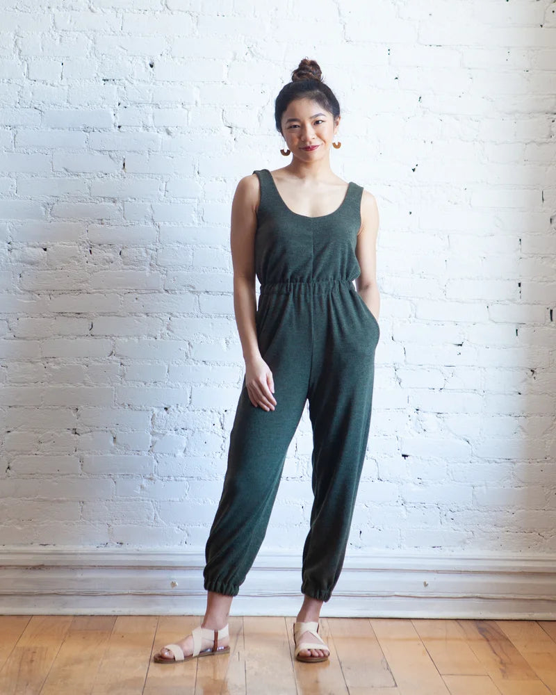 Woman wearing the Nova Jumpsuit sewing pattern from True Bias on The Fold Line. A sleeveless jumpsuit pattern made in knit fabrics such as cotton interlock or T-shirt jersey fabrics, featuring a scoop neckline, wide elastic waistband, inseam pockets, trou