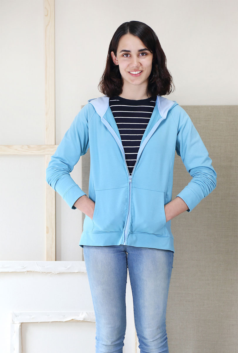 Woman wearing the Neighborhood Sweatshirt/Hoodie sewing pattern from Liesl + Co on The Fold Line. A hoodie pattern made in cotton jersey, interlock, french terry, sweatshirt fleece, or ponte di roma fabrics, featuring a raglan sleeve, front-zip, princess-