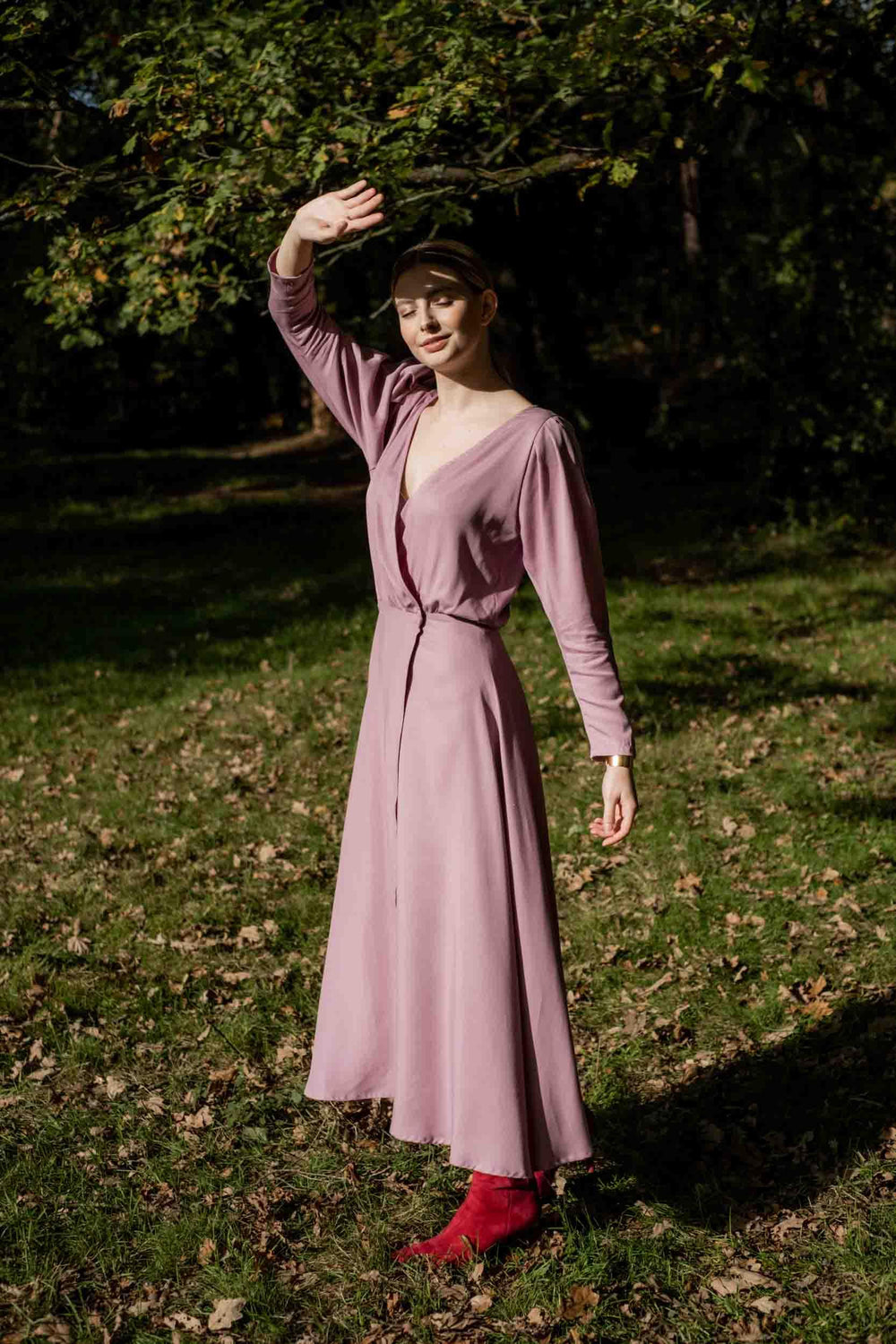 Woman wearing the Octavia Dress sewing pattern from Fibre Mood on The Fold Line. A wrap dress pattern made in crepe, linen, satin, lyocell, or muslin fabrics, featuring pleated cap sleeves tapered towards the wrist, bracelet length sleeves, bodice waist g