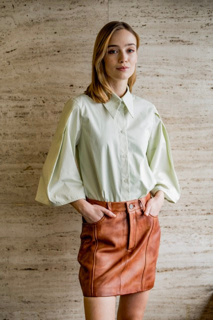 Woman wearing the Odyna Blouse sewing pattern from Fibre Mood on The Fold Line. A shirt pattern made in poplin, textured cotton, double gauze, chambray, lyocell, or crepe fabric, featuring a loose fit, button front, A-line pleated sleeve or long straight 