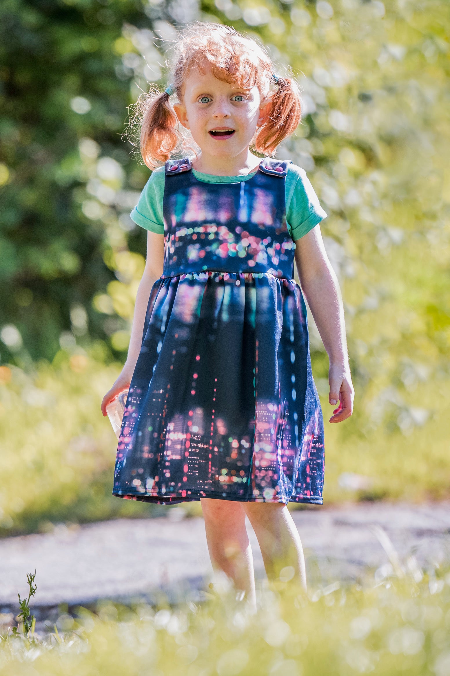 Child wearing the Over More Dress sewing pattern from Waves & Wild on The Fold Line. A pinafore pattern made in cotton/Lycra french terry, sweatshirt fleece or cotton/Lycra jersey fabrics, featuring a gathered skirt, in-seam pockets and tie shoulders.