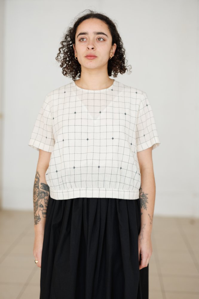 Woman wearing the Celeste Top sewing pattern from Merchant & Mills on The Fold Line. A blouse pattern made in cotton lawn or voile, cotton poplin, tencel, Indian handlooms, or cotton double gauze fabric, featuring a round neckline, short sleeves, back but
