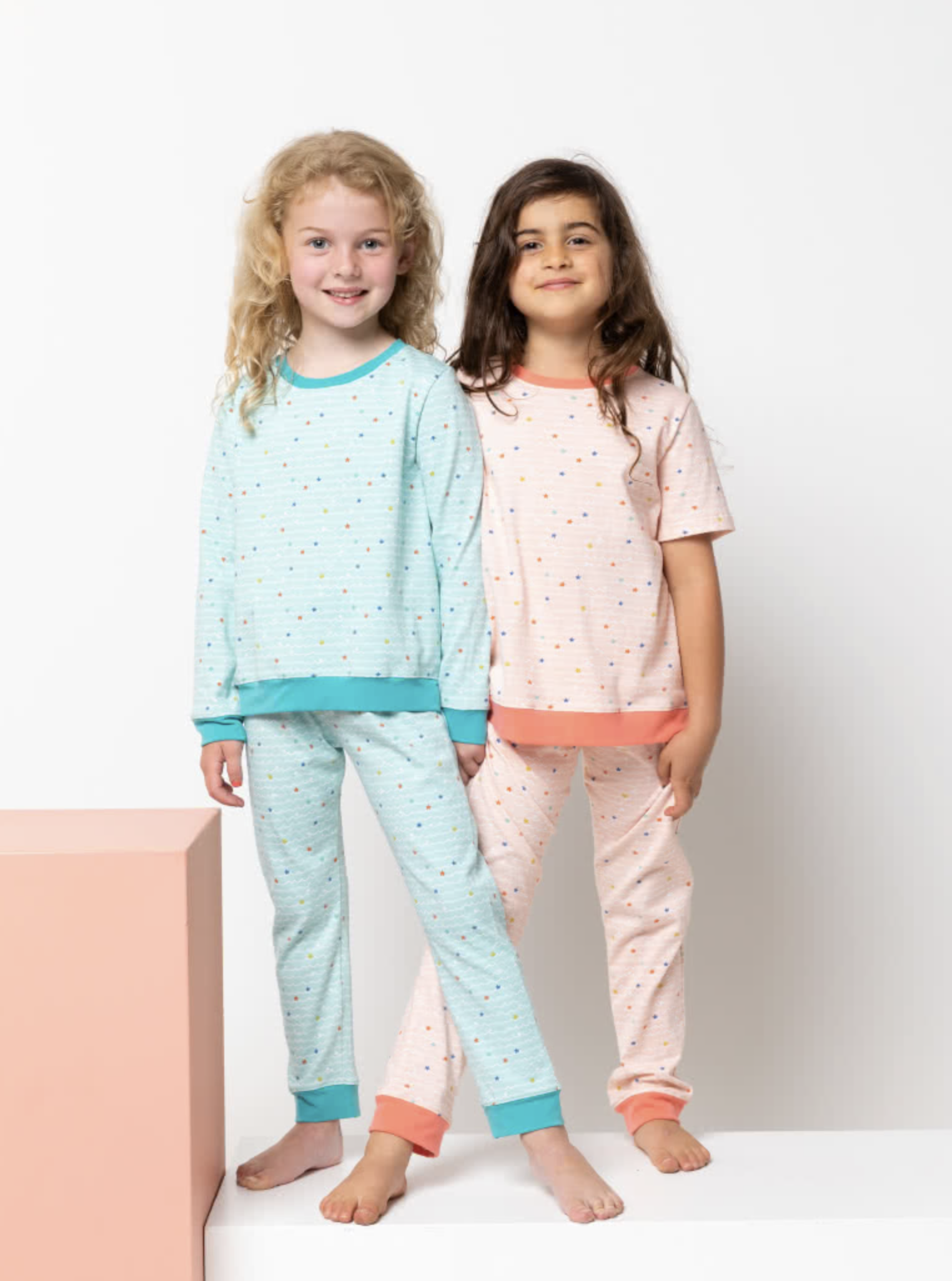 Children wearing the Baby/Child PJ Set sewing pattern from Style Arc on The Fold Line. A pyjamas pattern made in knit jersey fabrics, featuring a pyjama top with long or short sleeves, crew neck, cuffs and hem band. Pyjama pant has elastic waist and cuff 