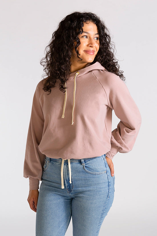 Woman wearing the Stanton Hoodie sewing pattern from Chalk and Notch on The Fold Line. A hoodie pattern made in French terry, fleece or jersey fabrics, featuring a cropped length, full length sleeves, draw string hood and relaxed fit.