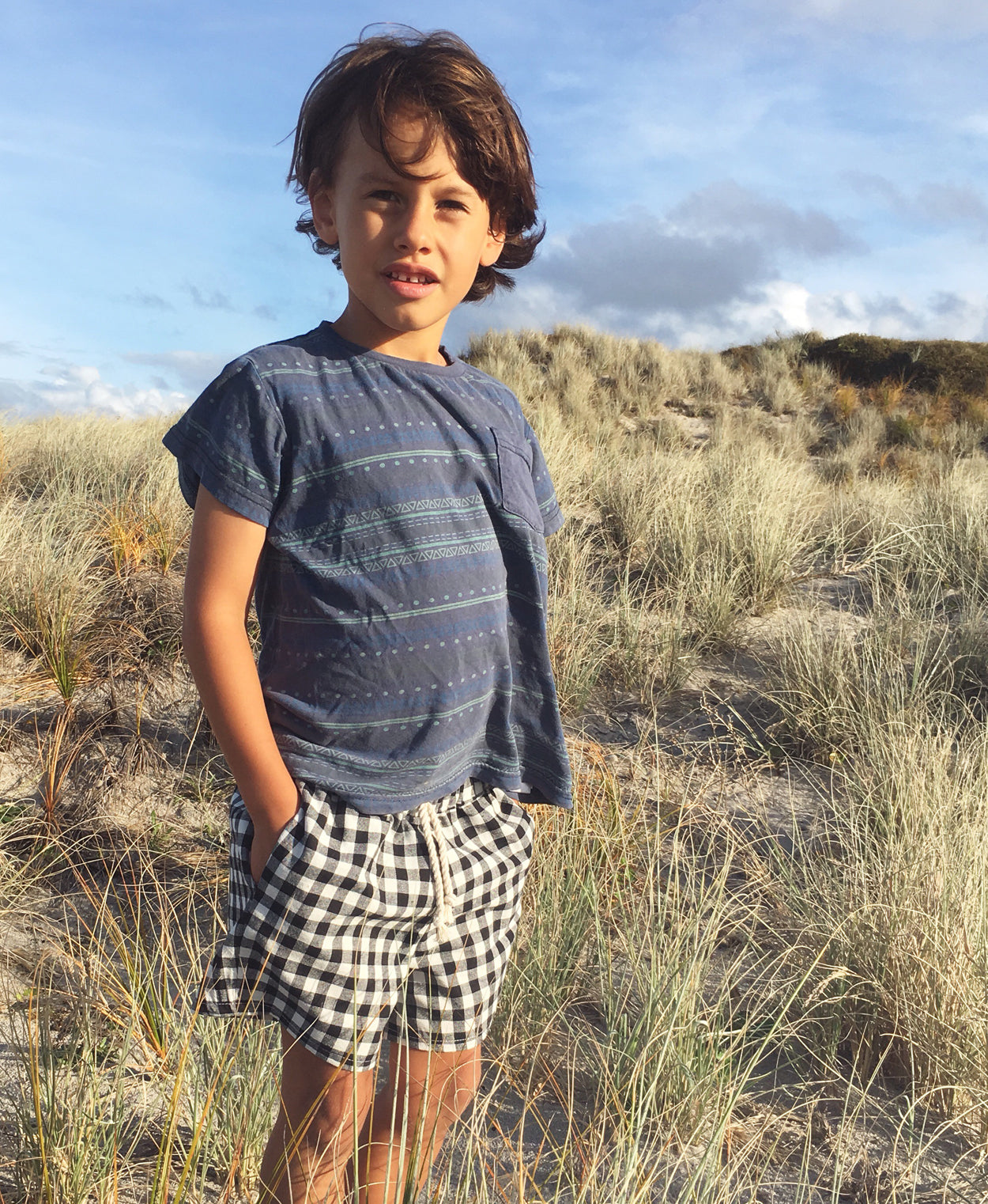 Child wearing the Pai Shorts sewing pattern from Below the Kōwhai on The Fold Line. A shorts pattern made in cotton, poly cotton, linen or chambray fabrics featuring a relaxed fit, above knee length, enclosed elastic waistband, drawstring and in-seam pock