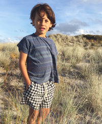 Child wearing the Pai Shorts sewing pattern from Below the Kōwhai on The Fold Line. A shorts pattern made in cotton, poly cotton, linen or chambray fabrics featuring a relaxed fit, above knee length, enclosed elastic waistband, drawstring and in-seam pock