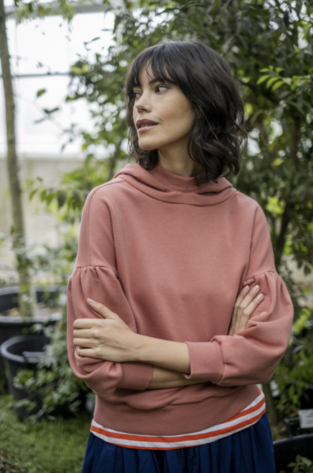 Woman wearing the Paola Sweater sewing pattern from Fibre Mood on The Fold Line. A hooded sweater pattern made in French terry, sweatshirt fabric, knit or ponte Roma fabrics, featuring a relaxed fitting hood, drop shoulder, ¾ length gathered sleeves, cuff