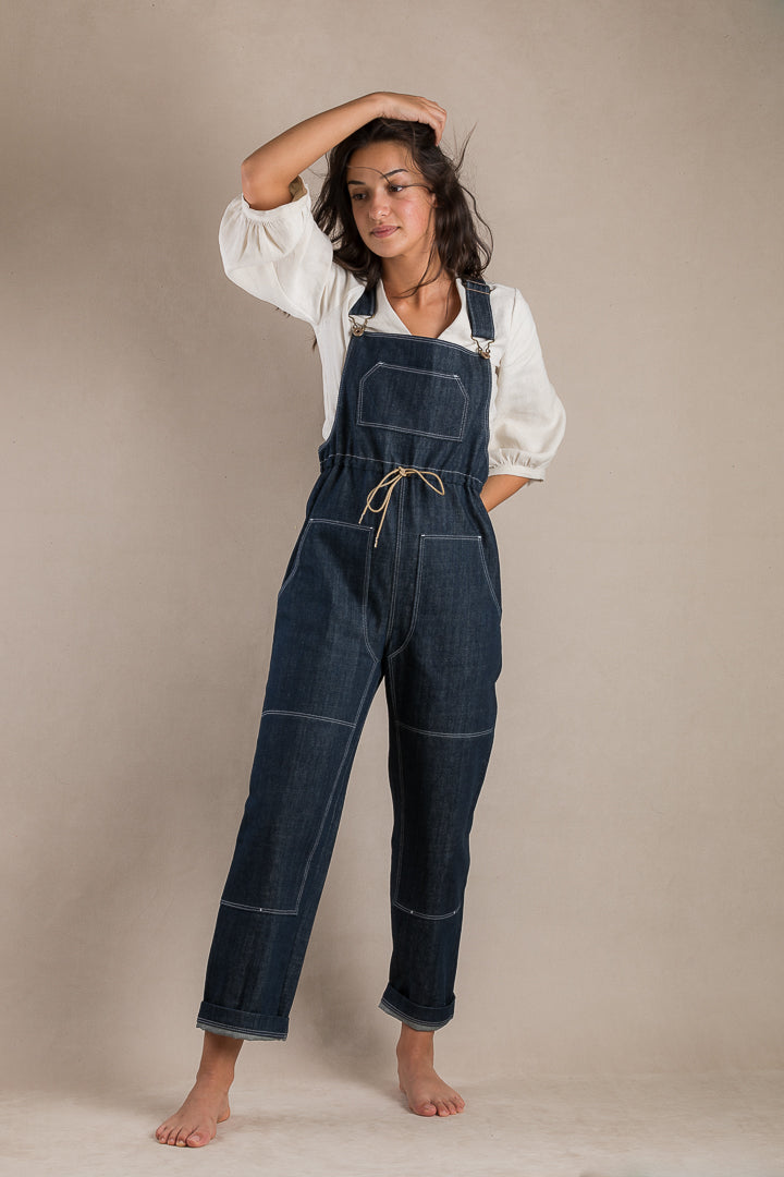 Woman wearing the Partner Overalls sewing pattern from Ready to Sew on The Fold Line. A dungarees/overalls pattern made in denim, twill, canvas, gabardine, moleskin or linen fabrics, featuring a straight-legged pant, adjustable drawstring waist, bib, four