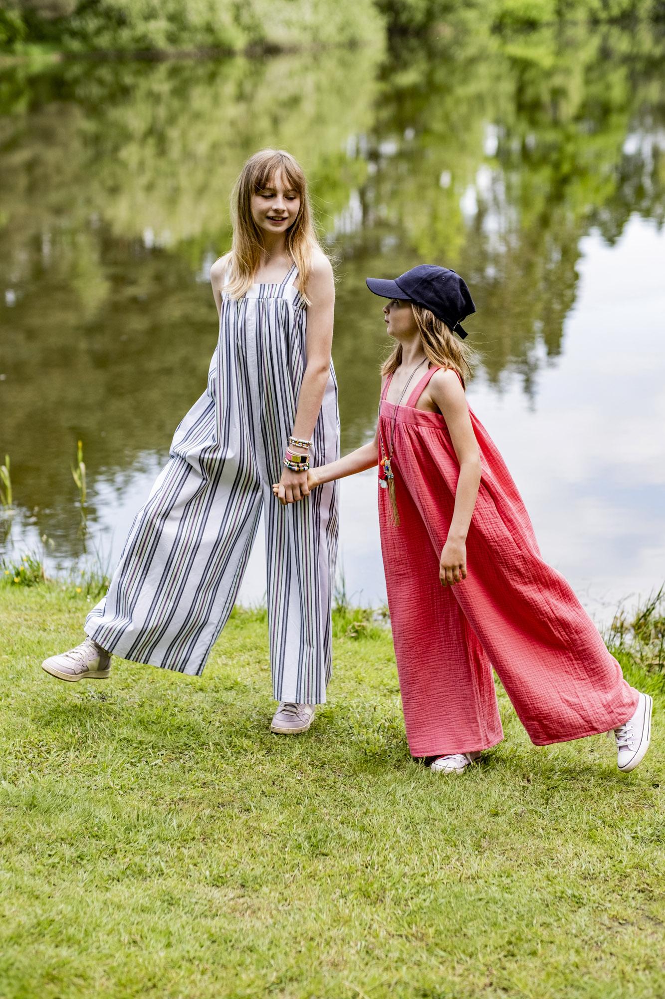 Children wearing the Children's Pearl Jumpsuit sewing pattern from Fibre Mood on The Fold Line. A jumpsuit pattern made in poplin, chambray, lyocell, double gauze, organza, seersucker or linen fabrics, featuring a relaxed fit, wide shoulder straps, side s