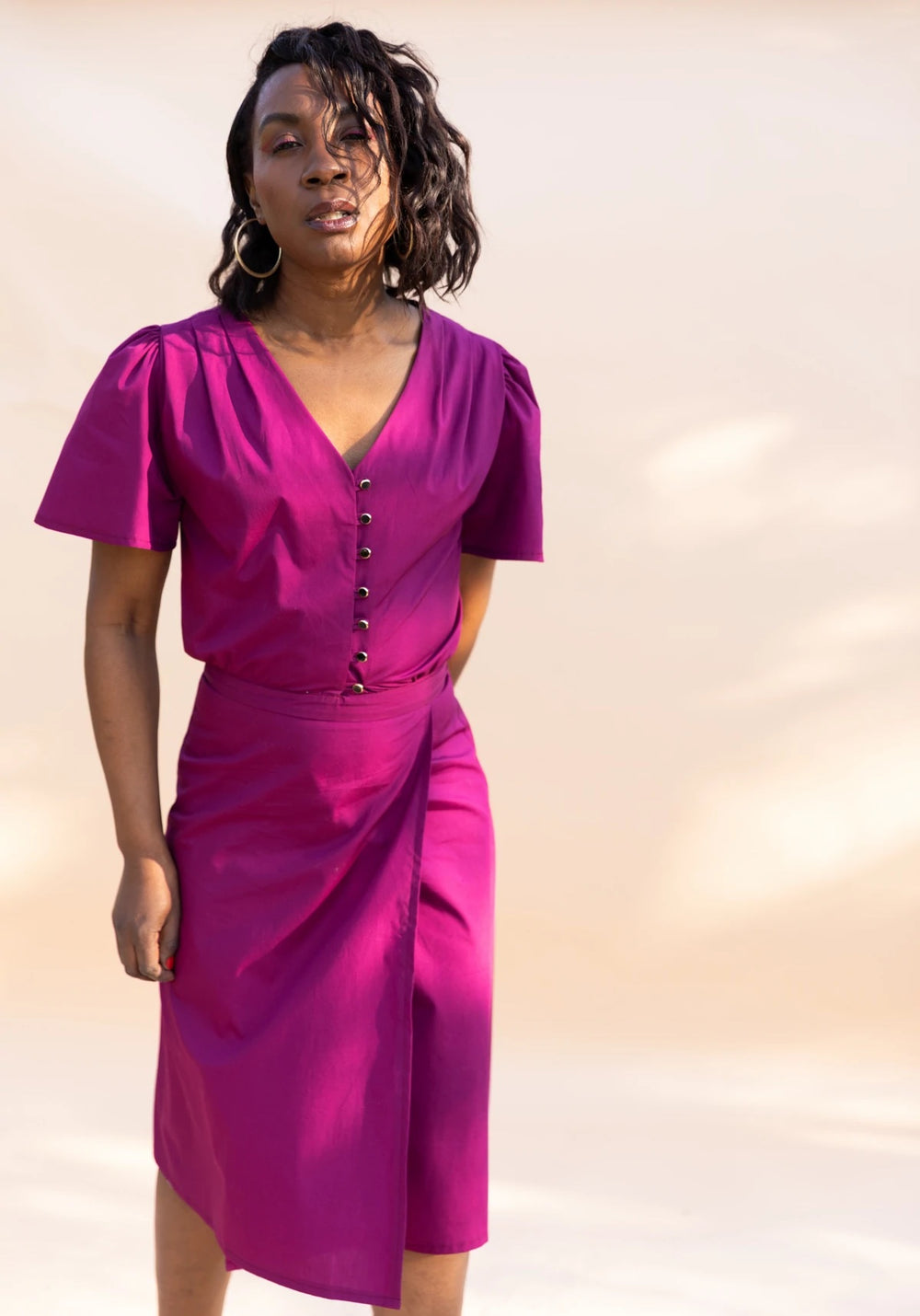 Woman wearing the Penelope Dress sewing pattern from Maison Fauve on The Fold Line. A wrap dress pattern made in viscose, cotton, linen, silk, poplin, crepe or satin fabrics, featuring a buttoned bodice, pleated shoulders, V-neck, short sleeves and below 