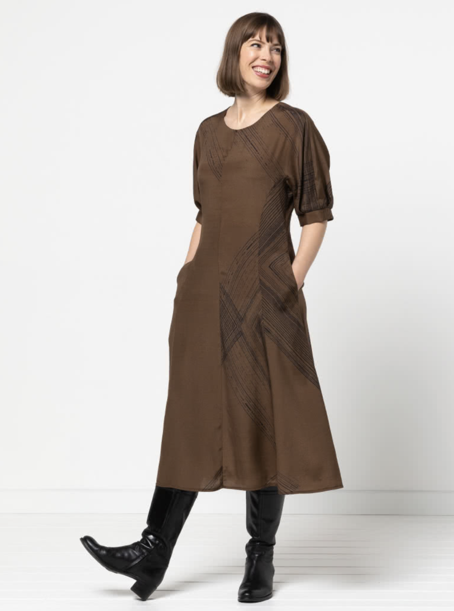 Woman wearing the Penelope Woven Dress sewing pattern from Style Arc on The Fold Line. A dress pattern made in silk, rayon, crepe or washed linen fabrics, featuring a midi length, semi fit, princess seams, elbow length sleeves with tucks and gussets, roun