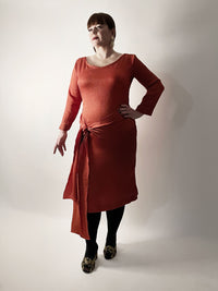 Woman wearing the No. 25 Penhouët Dress and Top sewing pattern from How to Do Fashion on The Fold Line. A dress pattern made in stretch knit or woven fabrics, featuring a fitted pencil dress silhouette, long sleeves, scoop neck, back vent, waist tie and j