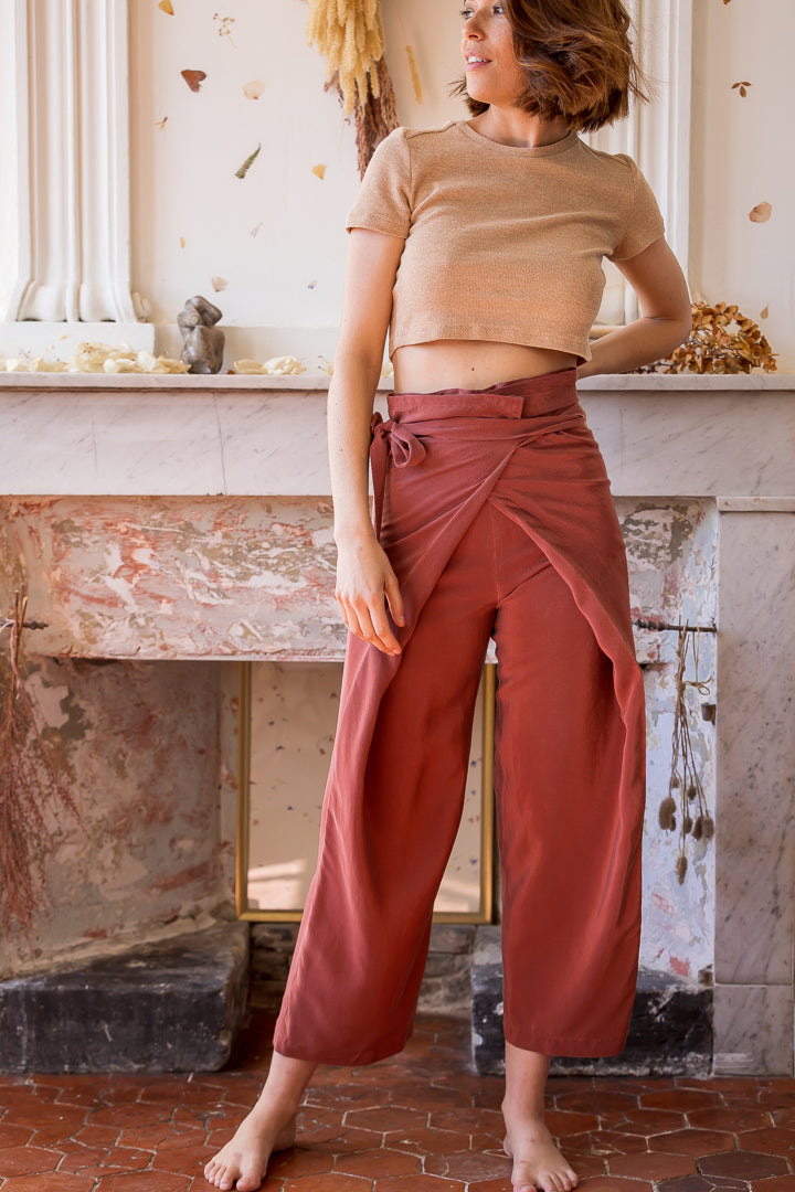 Woman wearing the Phen Wrap Pants sewing pattern from Ready to Sew on The Fold Line. A wrap trouser pattern made in linen or ramie fabrics, featuring a balloon leg, waist knot closure, two front darts, four back darts, back patch pockets, and cropped leng