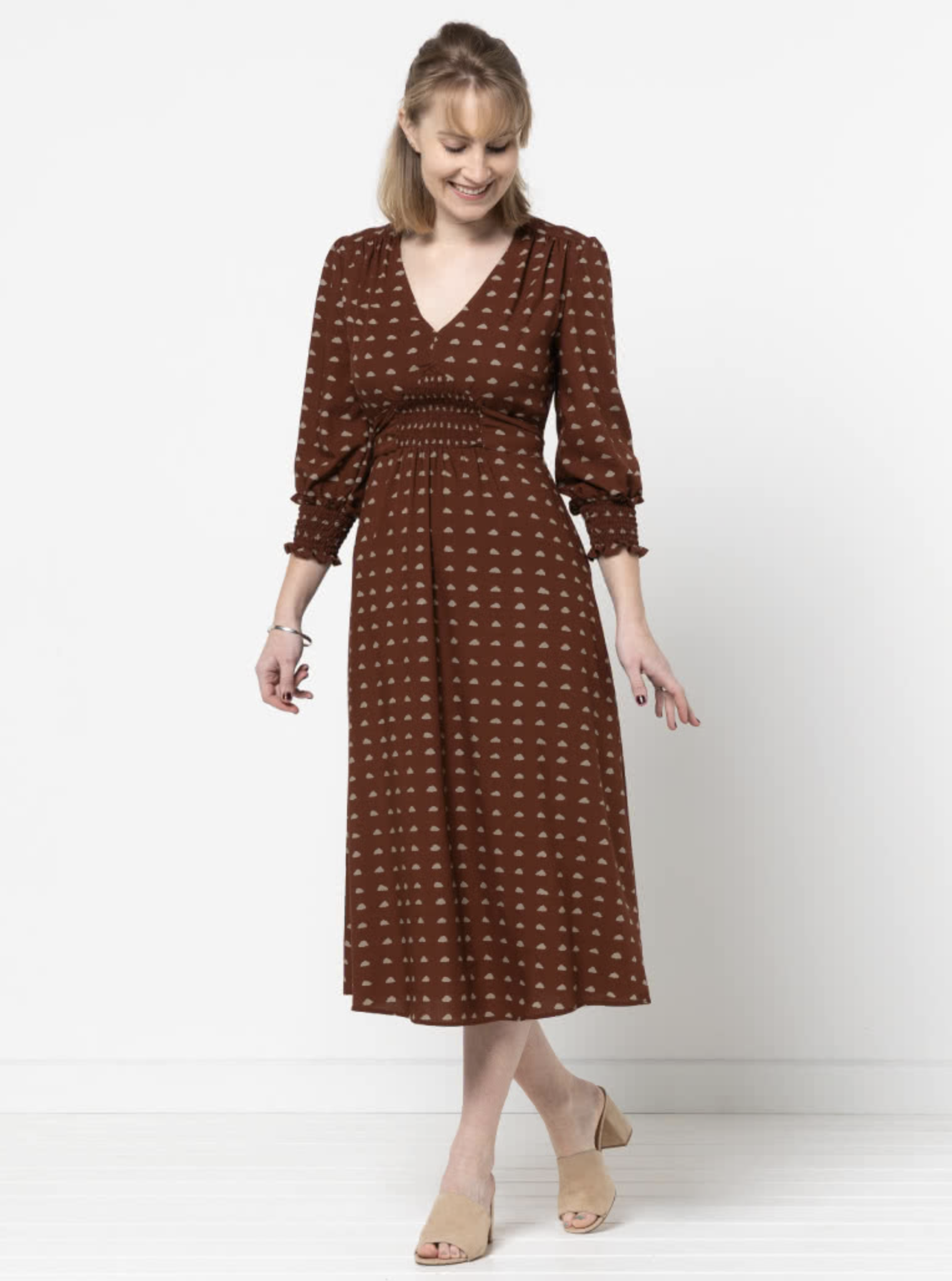 Woman wearing the Philomena Woven Dress sewing pattern from Style Arc on The Fold Line. A dress pattern made in silk, rayon, crepe or viscose fabrics, featuring a V-neck, fitted bodice, shirred waist insert, tie belt, midi length, 3/4 length sleeves with 