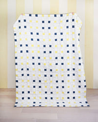 Photo showing the Picnic Square Quilt sewing pattern from Matchy Matchy on The Fold Line. A quilt pattern made in quilting cotton fabrics, featuring squares and rectangles, using the chain piecing method, use solid, prints or scrap collection fabrics.