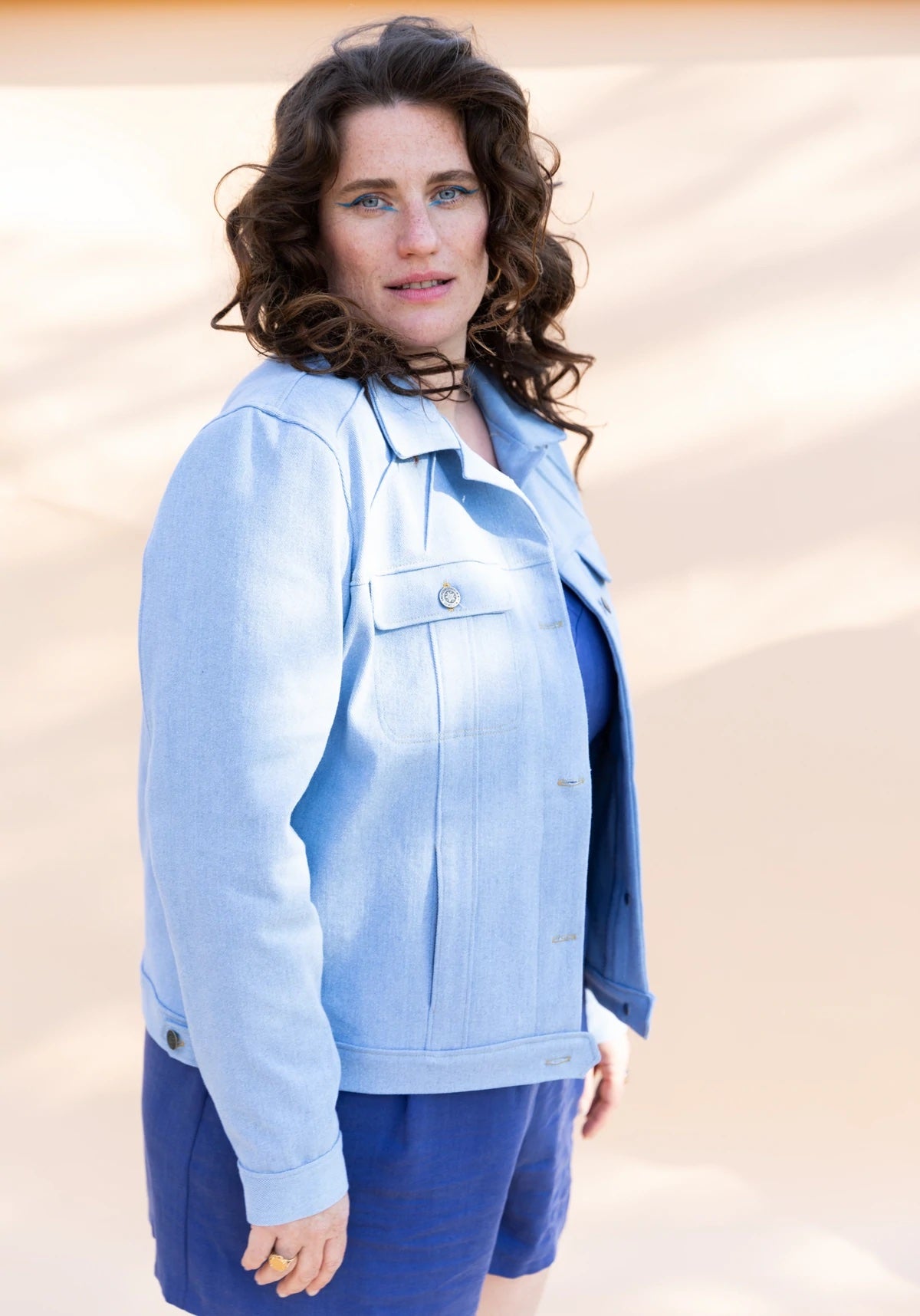 Woman wearing the Pilar Jacket sewing pattern from Maison Fauve on The Fold Line. A denim jacket pattern made in denim, wool, jacquard or gabardine fabrics, featuring a flat collar, front yoke with stitched darts, back yoke, front button closure, front ch