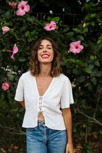 Woman wearing the Plumeria Top sewing pattern from Paradise Patterns on The Fold Line. A blouse pattern made in silk crepe, charmeuse, rayon twill, challis, tencel, modal, or linen blend fabrics, featuring a relaxed fit, low V-neck, bust darts, lace-up cl