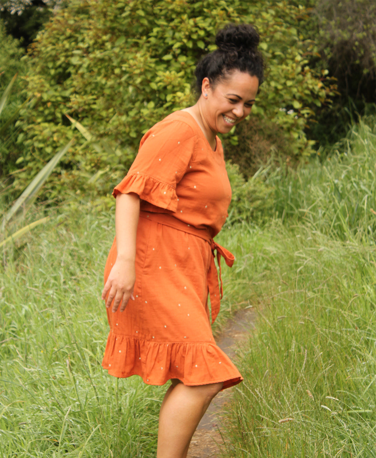 Woman wearing the Pōhutukawa Dress sewing pattern by Below the Kowhai. A shift style dress pattern made in light to medium weight cotton, chambray, poly cotton, linen, rayon, sateen or tencel fabrics, featuring short sleeves, hem ruffle, inseam pockets, a