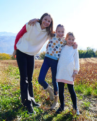 Children wearing the Quileute Sweatshirt and Dress sewing pattern from Petits D'om on The Fold Line. A sweatshirt and dress pattern made in sweatshirt fabrics, featuring a straight cut, dropped shoulders, long sleeves with cuffs or sleeveless, hem band wi