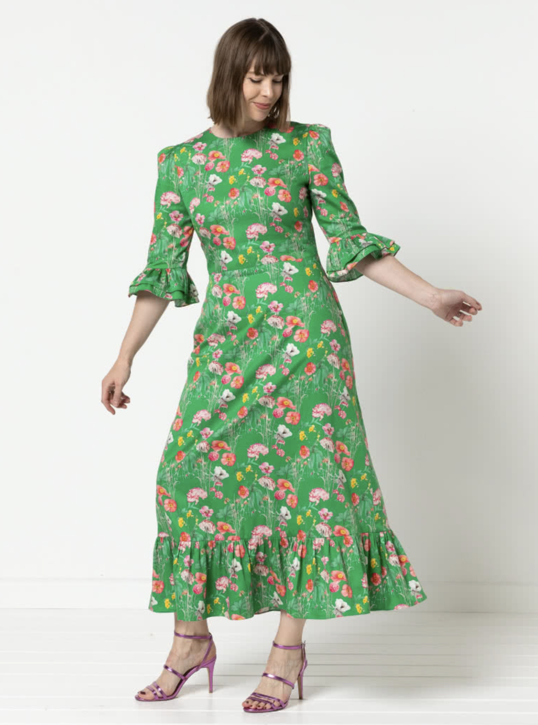 Woman wearing the Queenie Woven Dress sewing pattern from Style Arc on The Fold Line. A dress pattern made in silk, rayon, or charmeuse fabric, featuring a darted fitted bodice, centre back zip, elbow length sleeve with a double frill and gathered head, a