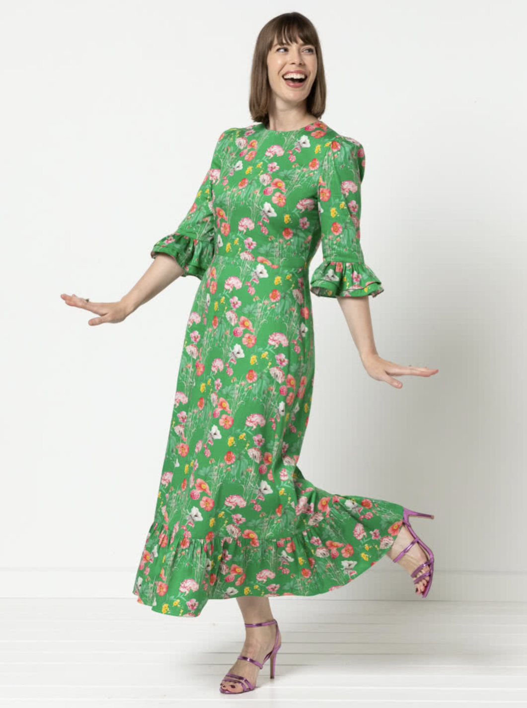 Woman wearing the Queenie Woven Dress sewing pattern from Style Arc on The Fold Line. A dress pattern made in silk, rayon, or charmeuse fabric, featuring a darted fitted bodice, centre back zip, elbow length sleeve with a double frill and gathered head, a