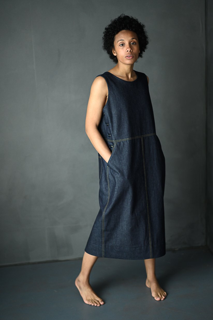 Woman wearing the Whittaker Dress pattern from Merchant and Mills on The Fold Line. A pinafore dress pattern made in denim, cotton twill or canvas, corduroy, moleskin, linen or tencel/linen blend fabrics, featuring a buttoned side fastening, side and back