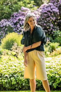 Woman wearing the Rachel Bermuda Shorts sewing pattern from Fibre Mood on The Fold Line. A shorts pattern made in poplin, chambray, linen, baby wale corduroy, gabardine or leather(ette) fabrics, featuring front double pleats, tailored back darts, side sea