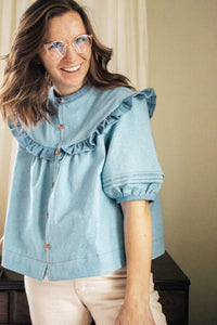 Woman wearing the Raida Blouse sewing pattern from Madswick on The Fold Line. A blouse pattern made in linen, cottons, lyocell, shirting, viscose crepe, or viscose-linen-noil fabrics, featuring a collar stand, circular yoke with ruffle, elbow length sleev