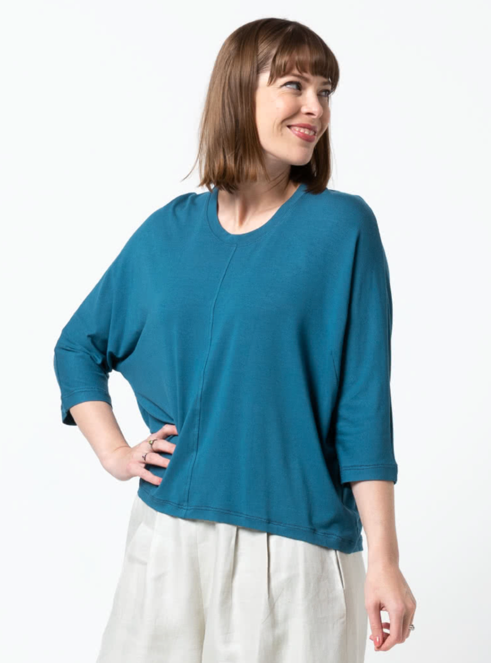 Woman wearing the Rhea Knit Top sewing pattern from Style Arc on The Fold Line. A knit top pattern made in knit jersey, baby wool or French terry fabrics, featuring a relaxed fit, hip-length, crew neck with neckband, bust darts, elbow-length dolman sleeve