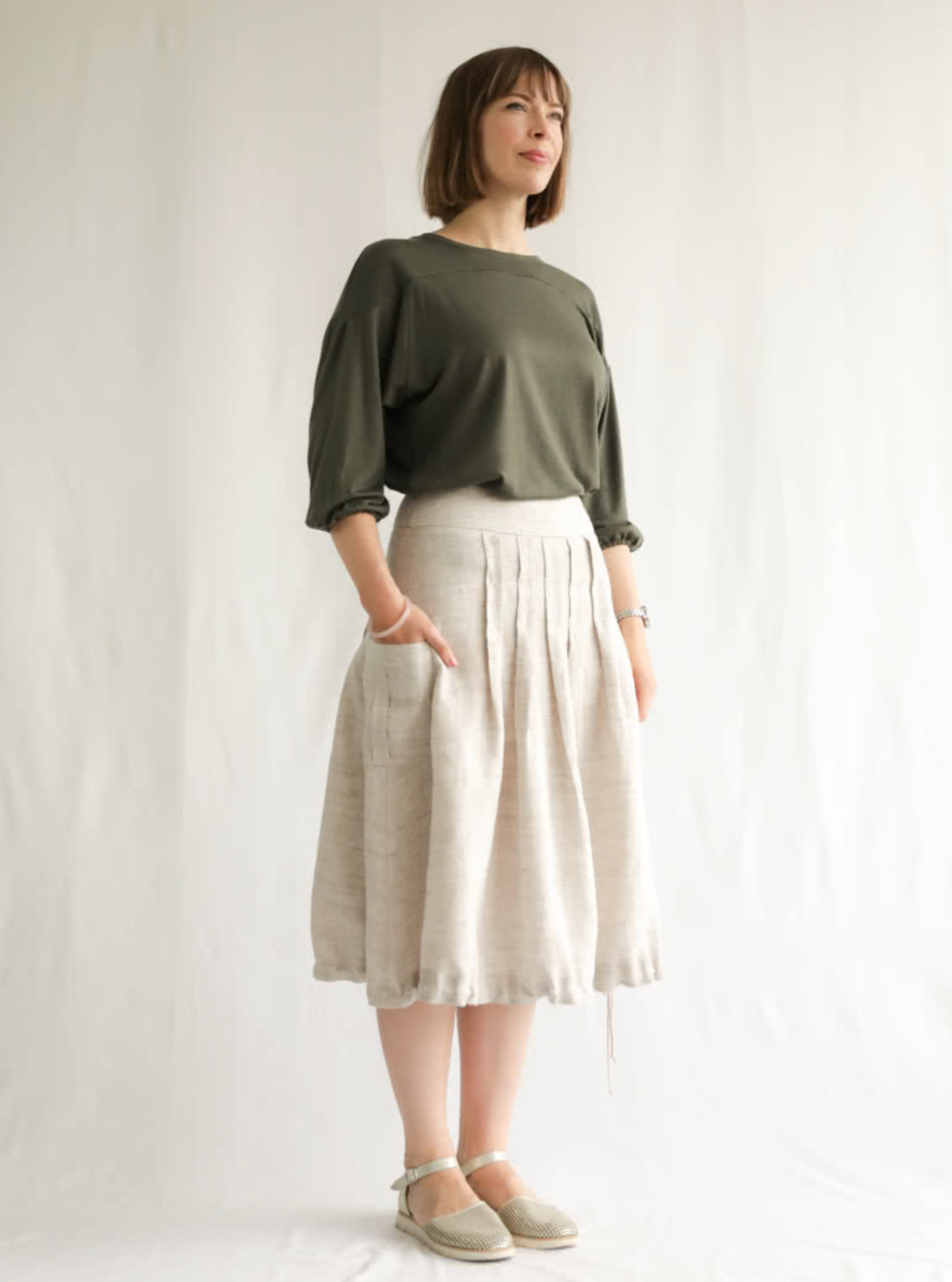Woman wearing the Richmond Utility Skirt sewing pattern from Style Arc on The Fold Line. A skirt pattern made in washed linen, poplin or crepe fabrics, featuring front and back topstitched box pleats, pockets with centre box pleat, side seam invisible zip